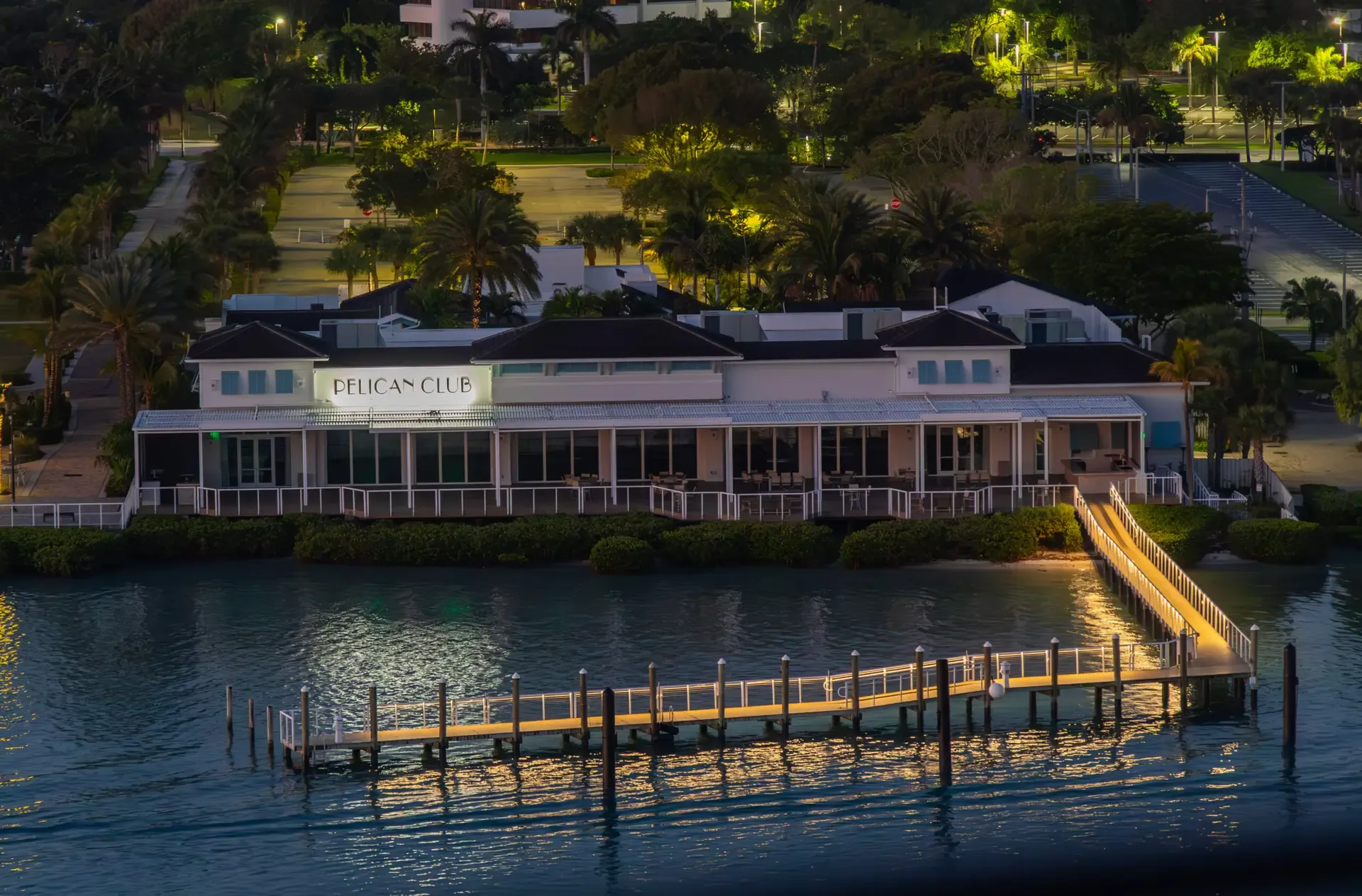 The Pelican Club restaurant lit at dusk with its long dock reaching out over the water