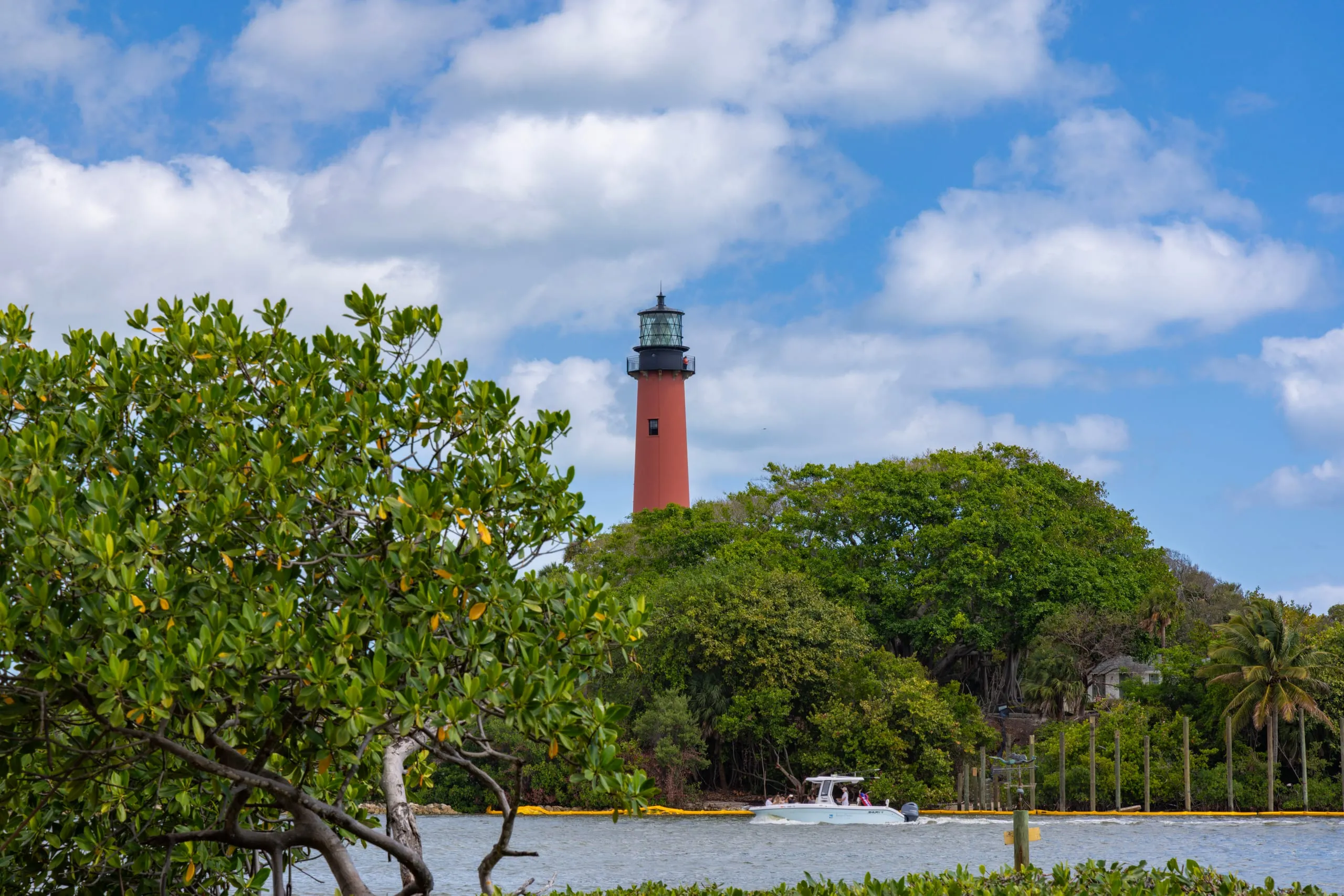 The Jupiter Inlet Lighthouse across the water with a boat heading out